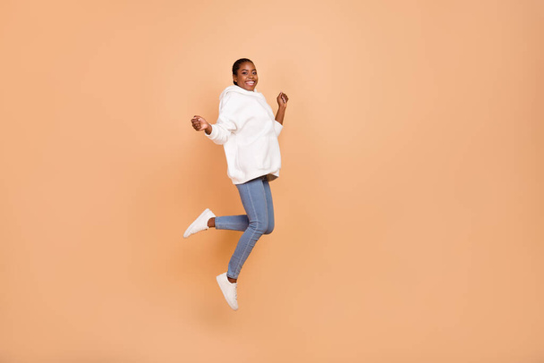 Full size photo of overjoyed energetic person have fun good mood jumping isolated on beige color background - Fotoğraf, Görsel