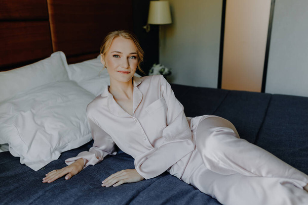  Bride morning. A beautiful young girl in pajamas lies on a bed in a hotel. High quality photo - Photo, Image