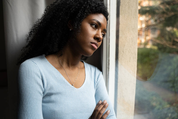Μια μαύρη γυναίκα με κατάθλιψη μπροστά από το παράθυρο - Φωτογραφία, εικόνα
