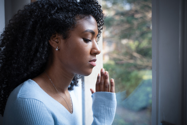 Een zwarte vrouw bidt voor het raam - Foto, afbeelding