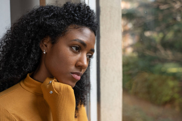A black woman very sad thinking in front of window - Zdjęcie, obraz