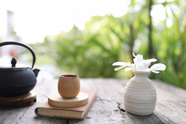 bambusz csésze és fém teáskanna barna notebook fa asztalon - Fotó, kép