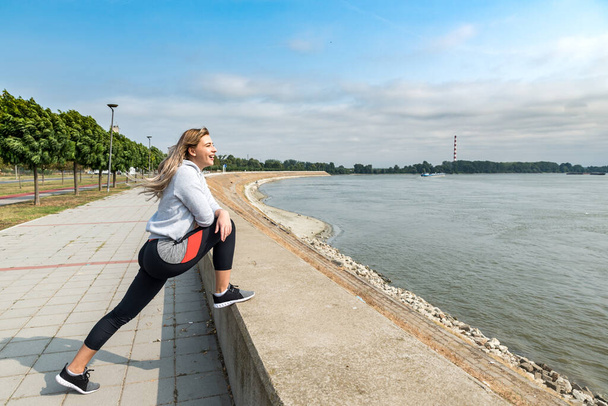Young woman starting new life after car crash accident or heavy illness with morning routine of exercising running and jogging outdoor. Female sport person stretching muscles before workout. - Photo, Image