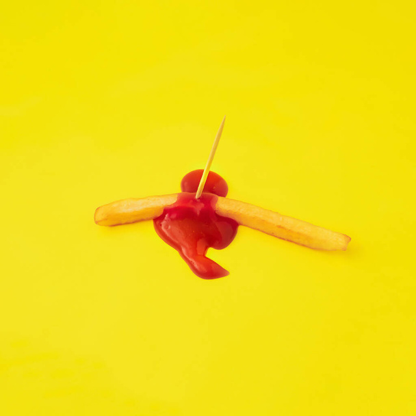 composition minimale créative de frites tuées avec cure-dent en bois à partir duquel il fuit ketchup sur fond jaune. - Photo, image