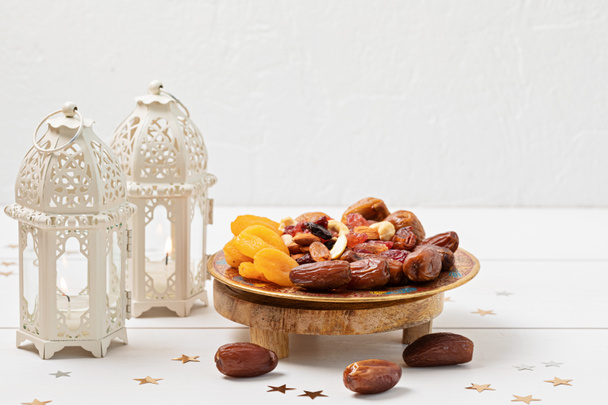 Ramadan Kareem και iftar muslim τροφίμων, έννοια των διακοπών. Δίσκοι με ξηρούς καρπούς και αποξηραμένα φρούτα και λάτερν με κεριά. Ιδέα εορτασμού - Φωτογραφία, εικόνα
