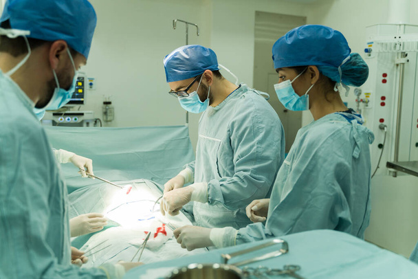 Χειρουργοί και ιατρική ομάδα που εκτελούν και χειρουργική επέμβαση έκτακτης ανάγκης σε τραυματισμένο ασθενή στο νοσοκομείο - Φωτογραφία, εικόνα