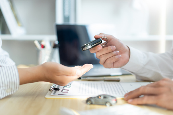 Concepto de seguro de la concesionaria de automóviles dando una llave de coche a su cliente después de firmar el contrato . - Foto, Imagen