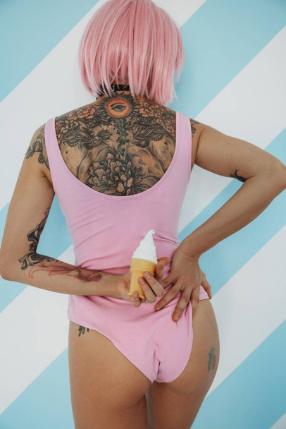 Back view of sensual young tattooed woman with pink hair with ice cream - Foto, immagini