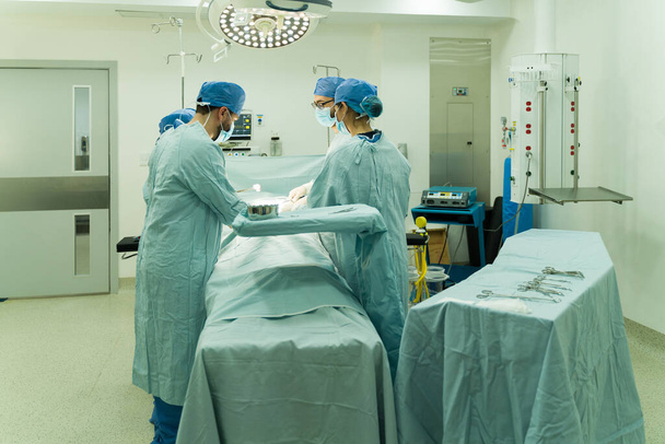 Vista posteriore del personale medico che lavora in sala operatoria ed esegue un intervento chirurgico d'urgenza su un paziente - Foto, immagini