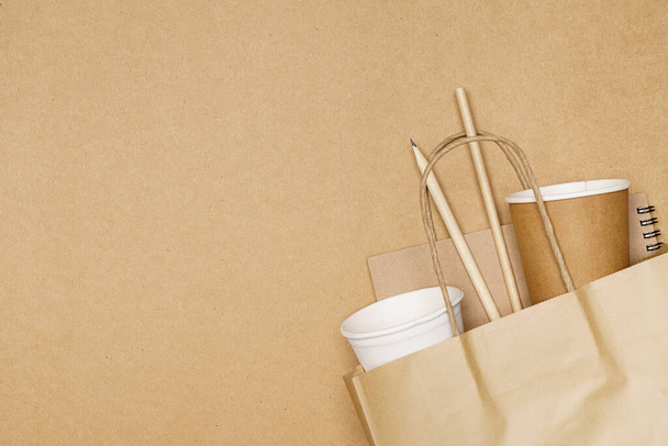 Conceito ecológico, lápis de notebook e copo de papel com palhas em saco de papel em fundo de madeira. - Foto, Imagem