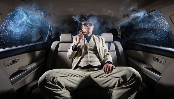 Een rijke man in een wit pak en een sigaar in de auto, een limousine. - Foto, afbeelding