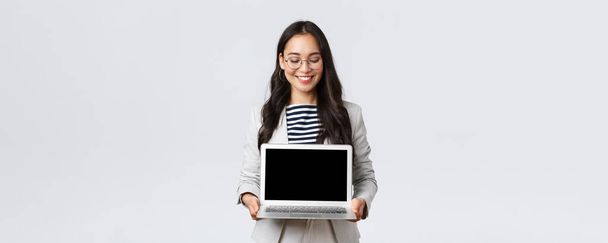 Business, finance and employment, female successful entrepreneurs concept. Enthusiastic businesswoman in suit and glasses showing presentation, demonstrate her project on laptop screen - Photo, image