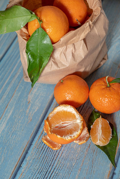 Paper bag with freshly picked mandarines on a wooden surface - Valokuva, kuva