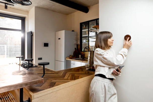 Frau steuert Wohntemperatur mit elektronischem Thermostat - Foto, Bild
