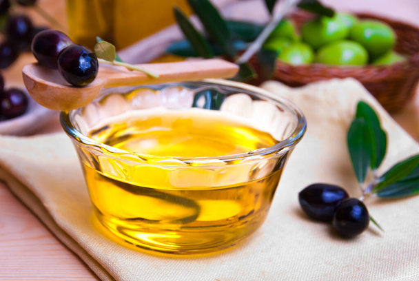 olive oil and olives on a wooden table - Fotó, kép