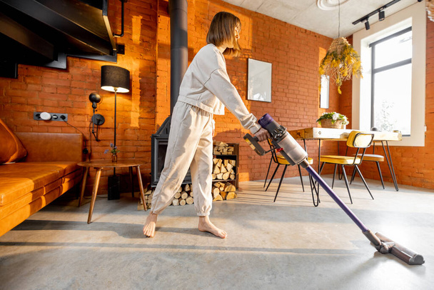 Frau reinigt Boden mit Handstaubsauger - Foto, Bild