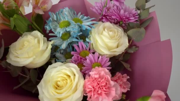 Közelkép egy gyönyörű csokor különböző virágok egy fényes rózsaszín csomag. - Felvétel, videó