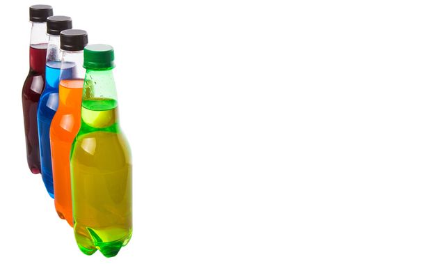Разноцветные содовые напитки в бутылках на белом фоне
 - Фото, изображение