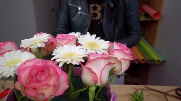 Primer plano de las manos de una florista femenina que empaca una hermosa composición - Imágenes, Vídeo