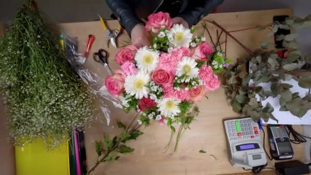 Primer plano de las manos de una florista femenina que empaca una hermosa composición - Imágenes, Vídeo