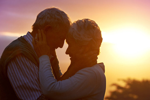 Aime-moi tendrement, aime-moi vrai.... Plan recadré d'un couple âgé partageant un moment romantique au coucher du soleil. - Photo, image