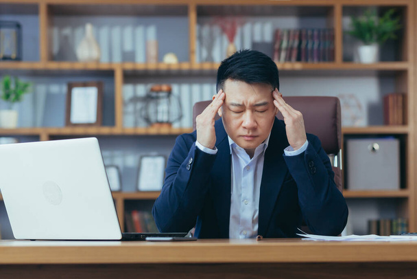 Asian businessman working in the office holding hands behind his head, tired has a severe headache, sick man at work - 写真・画像