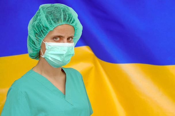 Chirurgien ou stagiaire portant un masque protecteur et un chapeau arrière-plan du drapeau ukrainien. Soins de santé, éducation médicale, services médicaux d'urgence, chirurgie ou concept vétérinaire - Photo, image