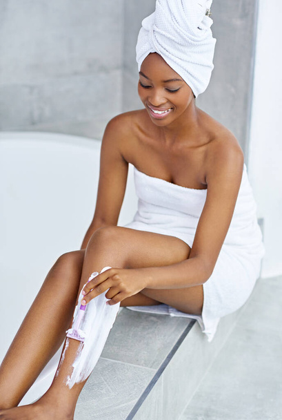 Rester sans poils et sans soucis. Plan grand angle d'une jeune femme se rasant les jambes par une baignoire. - Photo, image
