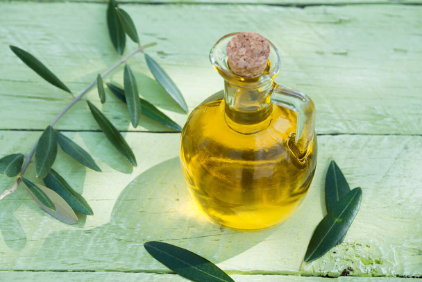 Оливковое масло в стеклянной бутылке на деревянном фоне
 - Фото, изображение