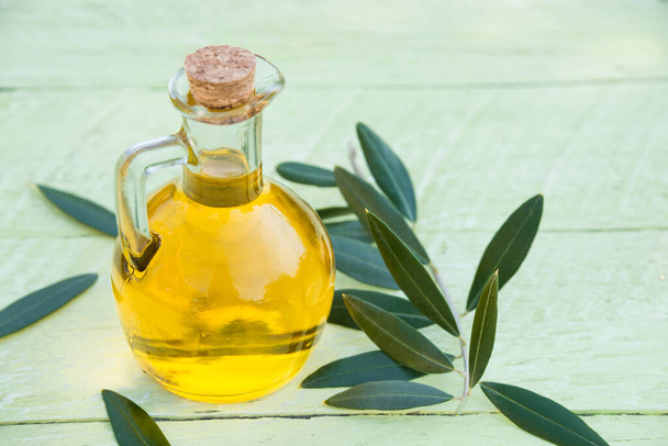 huile d'olive et feuilles vertes sur fond bois - Photo, image