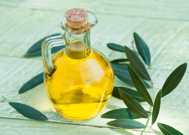 olive oil in a glass bottle on a wooden background - Foto, Imagem