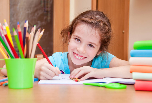 милая маленькая девочка рисует карандашами дома  - Фото, изображение