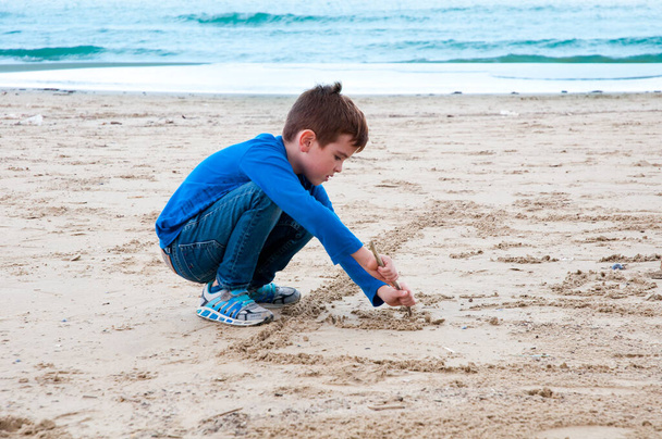 Pieni poika leikkii hiekalla rannalla - Valokuva, kuva