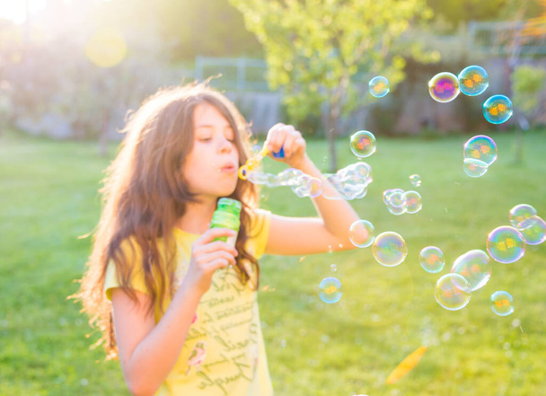 girl blowing soap bubbles in summer park - Foto, Imagen