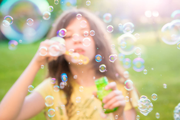 girl blowing soap bubbles in summer park - Fotografie, Obrázek