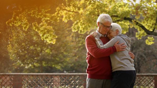 Couple caucasien âgé câlin dans le parc bien-être personnes âgées soutenir concept sélectif focus copier espace plan moyen  - Photo, image