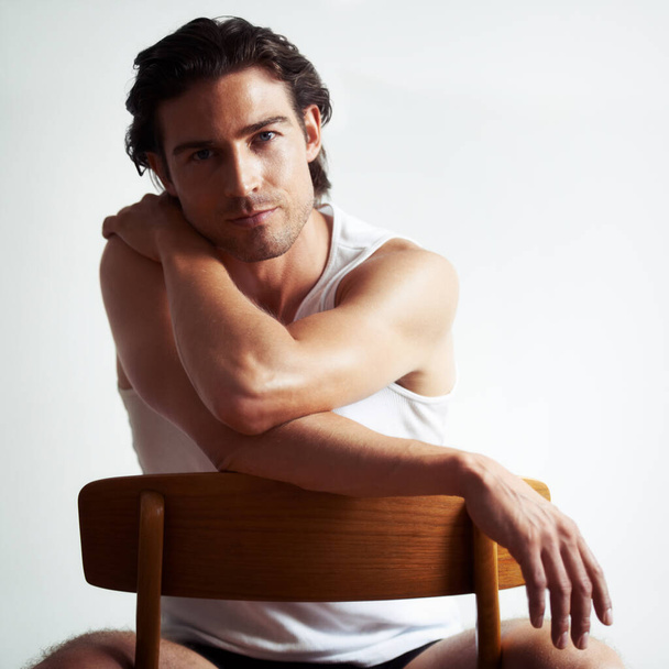 He has a sensual stare. Portriat of a handsome young man sitting on a chair. - Foto, immagini
