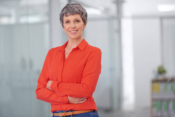 Its passion and commitment that drives my business. Portrait of a mature businesswoman standing with her arms crossed in an office setting. - Фото, изображение