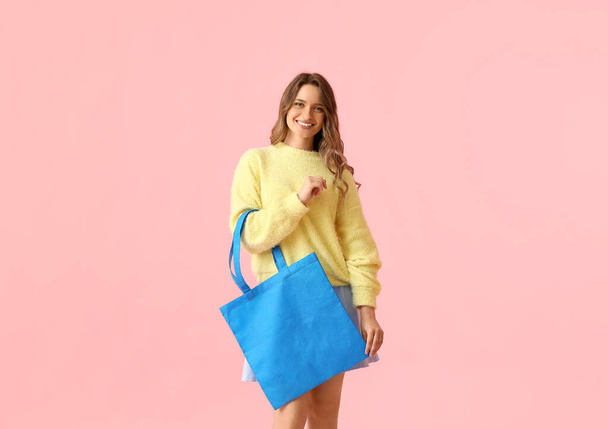Pretty young woman with blue eco bag on pink background - Foto, Imagen