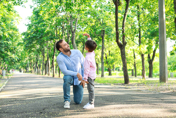 A kisfiú mutat valamit az apjának a parkban. - Fotó, kép
