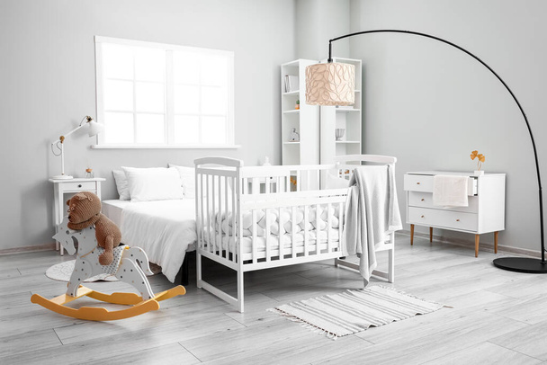Interior of stylish bedroom with bed, crib and toy bear on rocking horse - Photo, Image