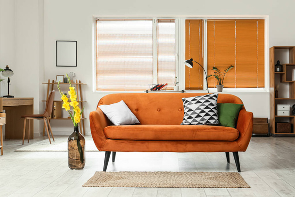 Interieur van stijlvolle woonkamer met comfortabele bank en gladiolen bloemen - Foto, afbeelding