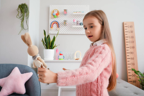 Schattig klein meisje met speelgoed konijn thuis - Foto, afbeelding