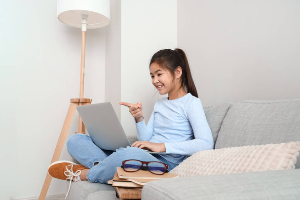 小さなアジアの女の子勉強とともにオンラインチューターにホーム - 写真・画像