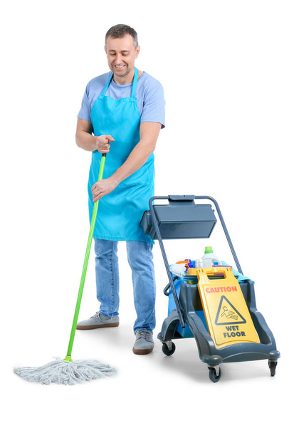 Volwassen werknemer van schoonmaak met trolley en benodigdheden op witte achtergrond - Foto, afbeelding