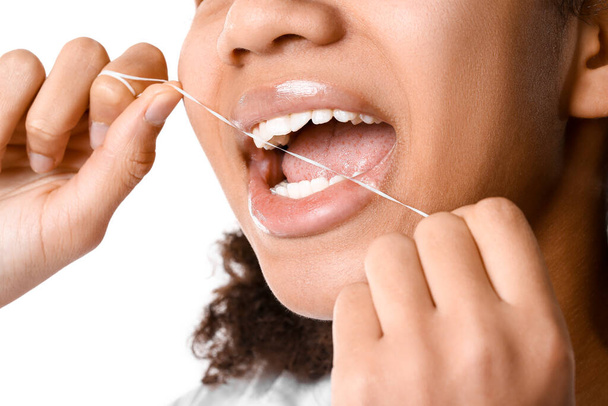 Afro-americano adolescente filo interdentale denti su sfondo bianco, primo piano - Foto, immagini