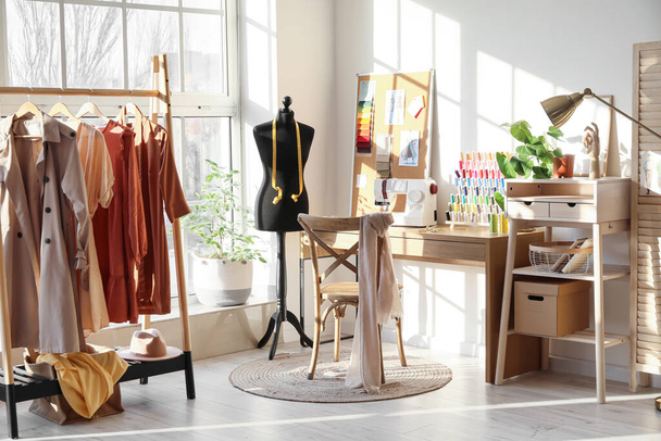 Interior of stylish atelier with tailor's workplace, mannequin and rack - Photo, Image