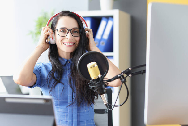 Όμορφη γυναίκα με ακουστικά μπροστά από το μικρόφωνο στο στούντιο - Φωτογραφία, εικόνα