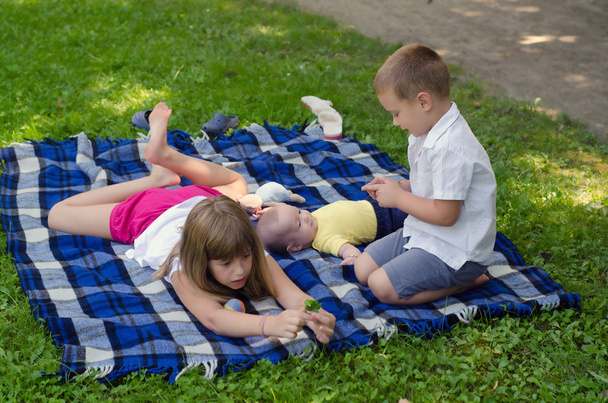 Older sister playing with two younger brothers on blanket - Foto, Imagen