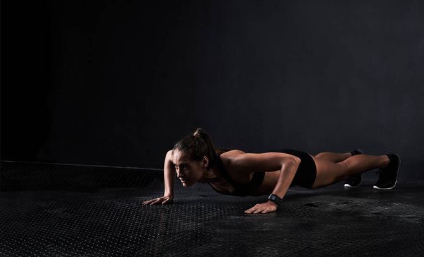 The perfect pushup. Studio shot of a woman working out against a dark background. - 写真・画像